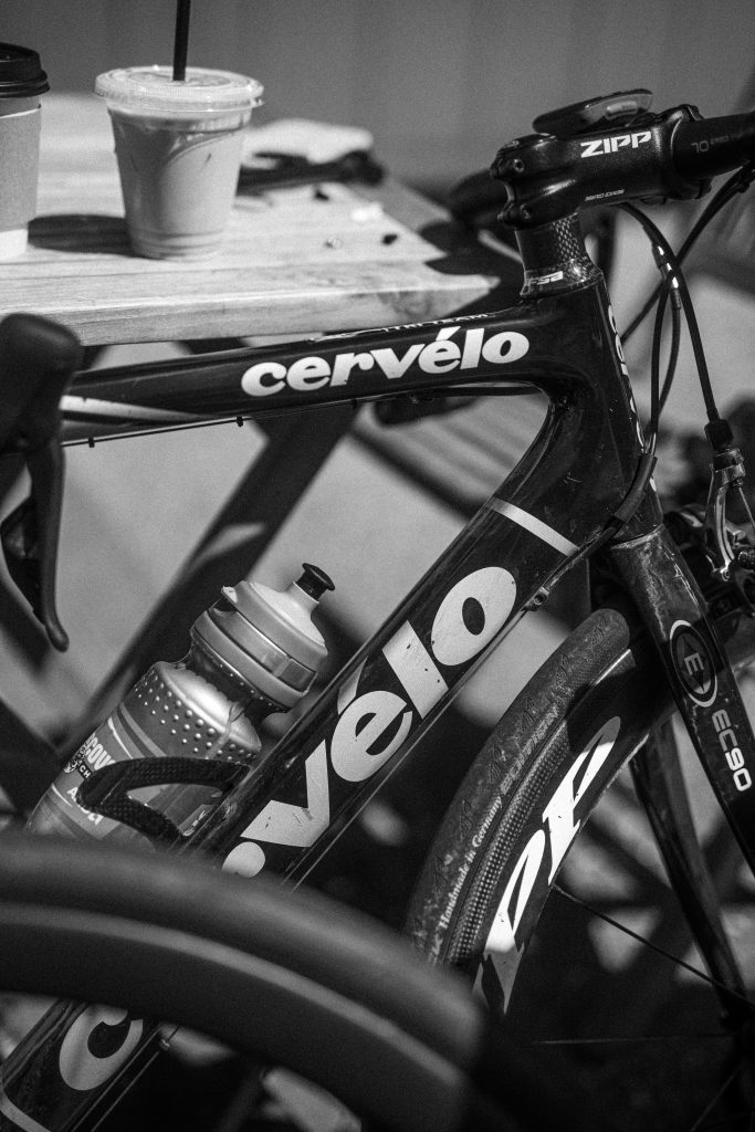 Photo en noir et blanc d'un vélo de route avec des tasses de café à proximité.