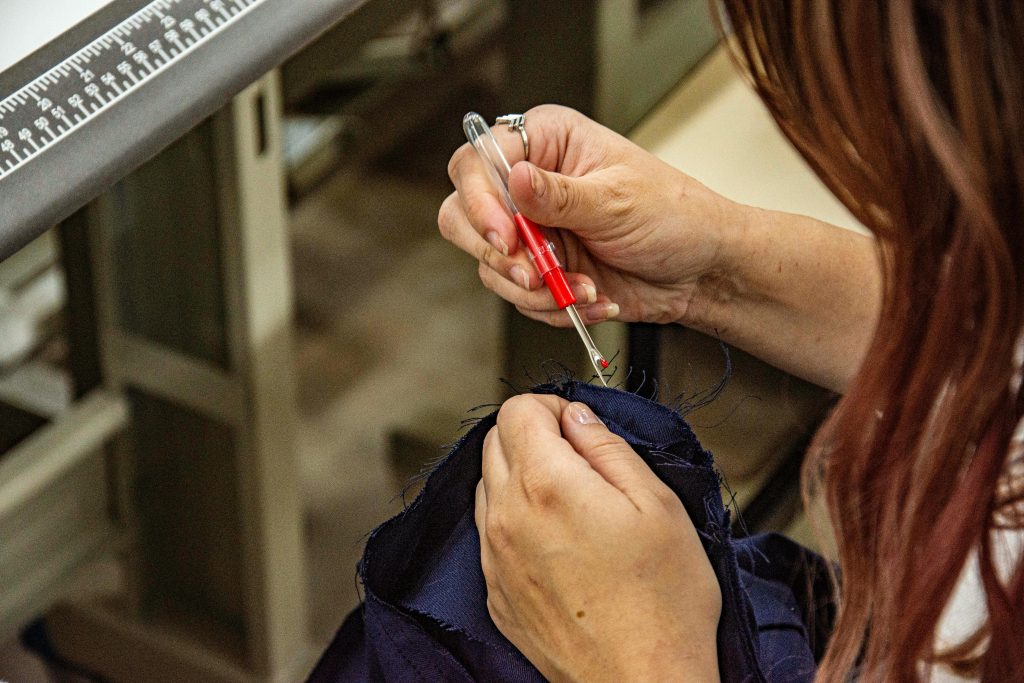 Détail des mains utilisant un découd-vite sur du tissu dans un atelier de couture à Apucarana, au Brésil.