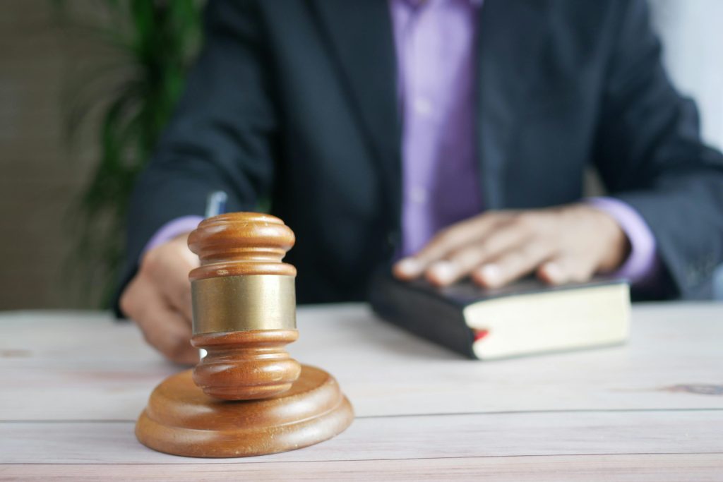 Un marteau en bois et un livre de droit représentent la justice dans un cadre judiciaire, mettant l'accent sur l'ordre et l'autorité légale.
