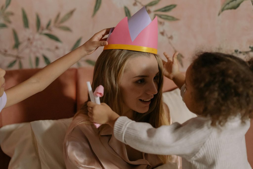 Mother et ses filles partagent un moment joyeux en jouant avec une couronne en papier à l'intérieur.