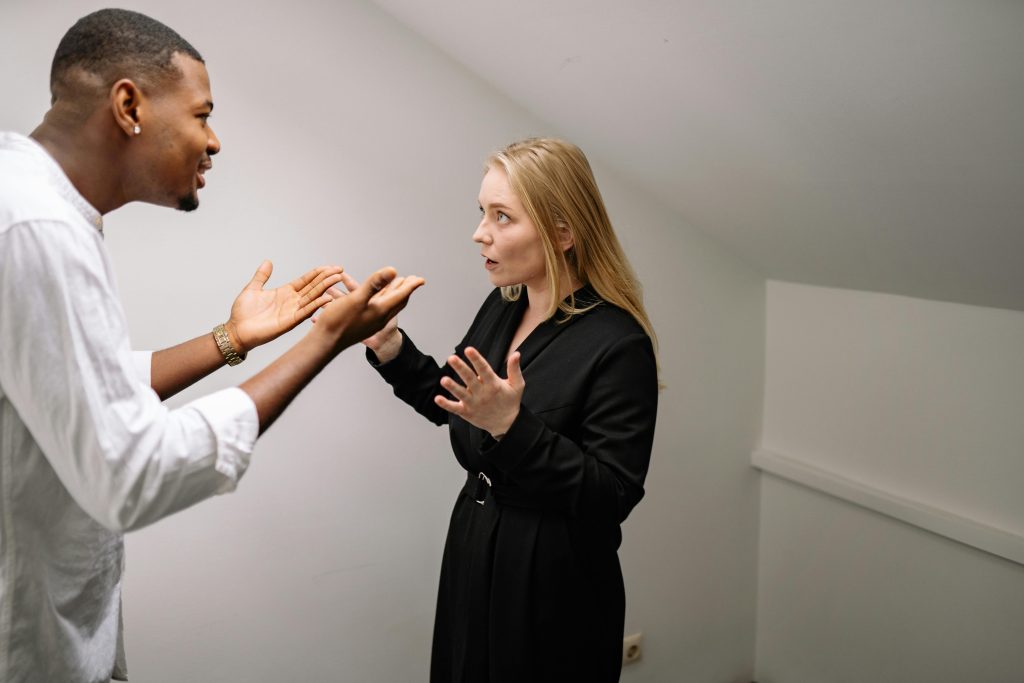 Un homme et une femme en pleine discussion animée dans un espace intérieur minimaliste.