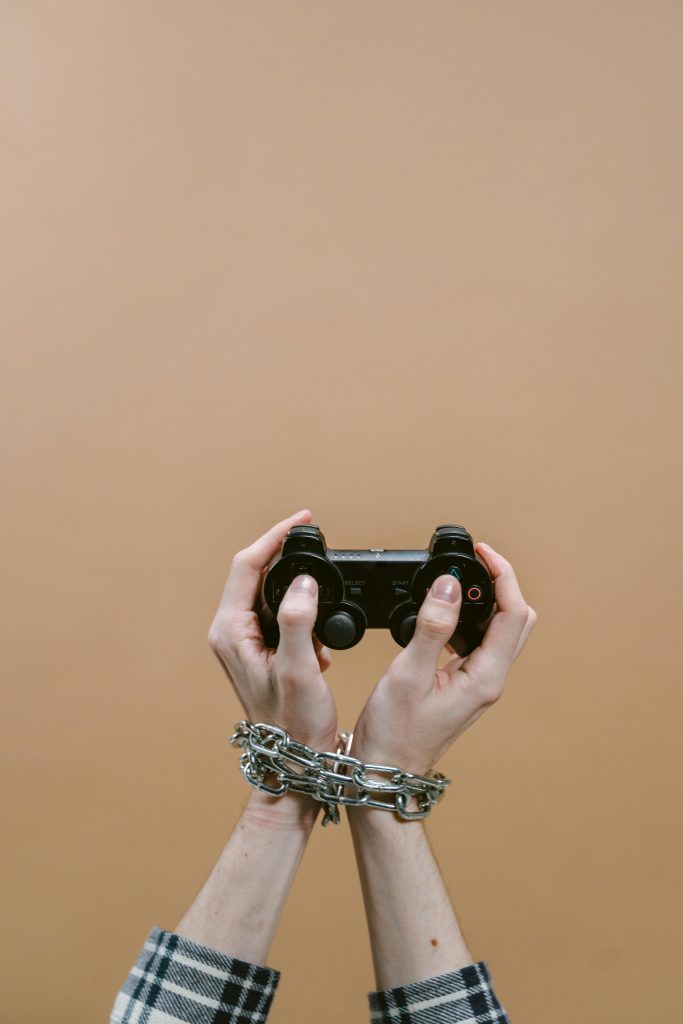 Mains enchaînées jouant à un jeu vidéo avec une manette illustrant le concept d'addiction numérique