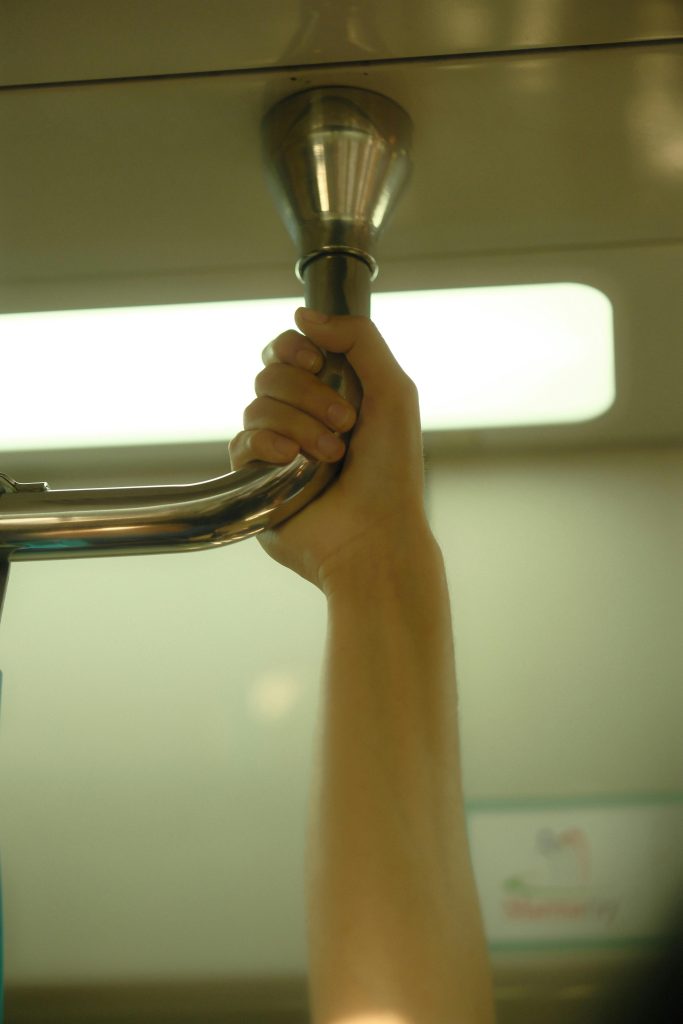 Une image en gros plan de la main d'une personne tenant fermement une rampe de métro.