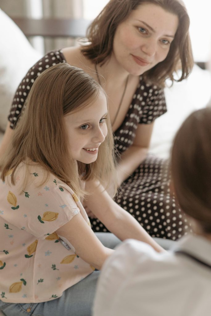 Une mère et une fille heureuses assises ensemble lors d'une consultation, souriant chaleureusement.