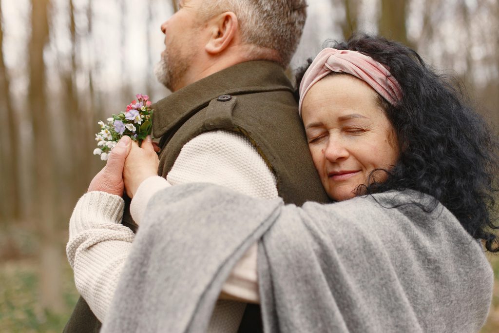 Un couple partage un moment tendre avec une étreinte par derrière dans une forêt en automne.