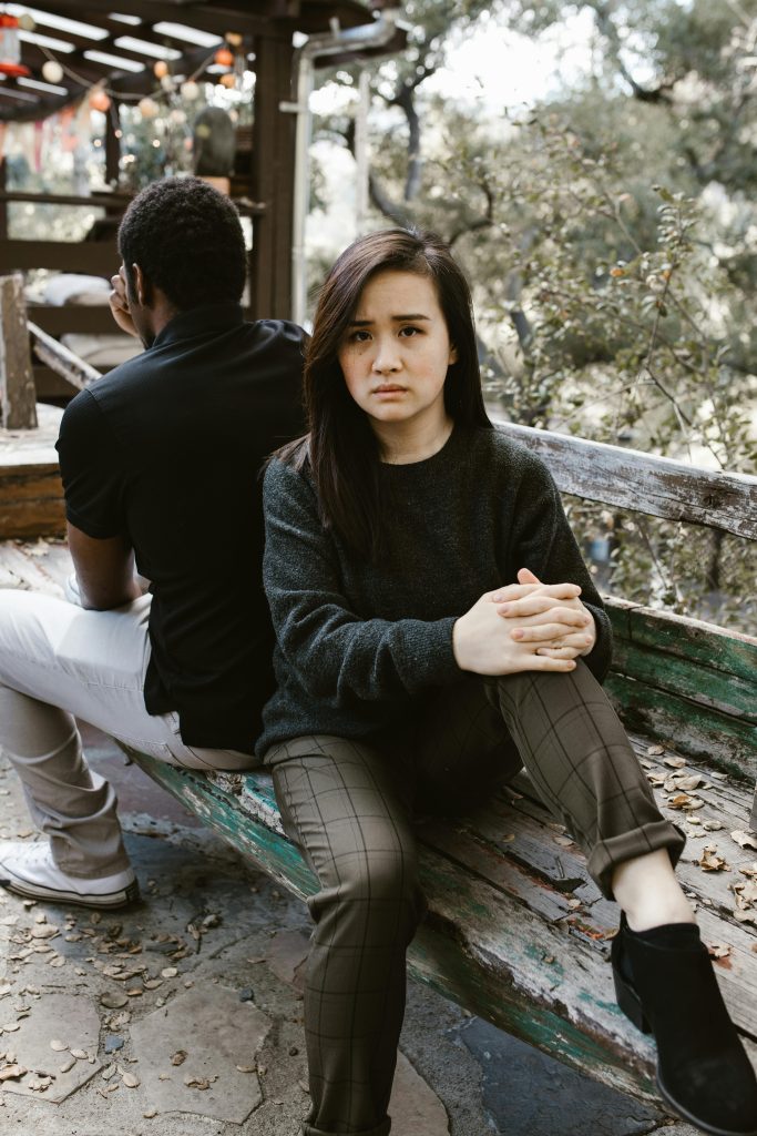 Un couple assis dos à dos sur un banc, exprimant de la tension et un conflit.