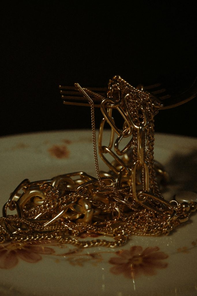 Gold chains delicately placed on a decorative porcelain plate, showcasing luxury. Des chaînes en or délicatement placées sur une assiette en porcelaine décorée, mettant en avant le luxe.