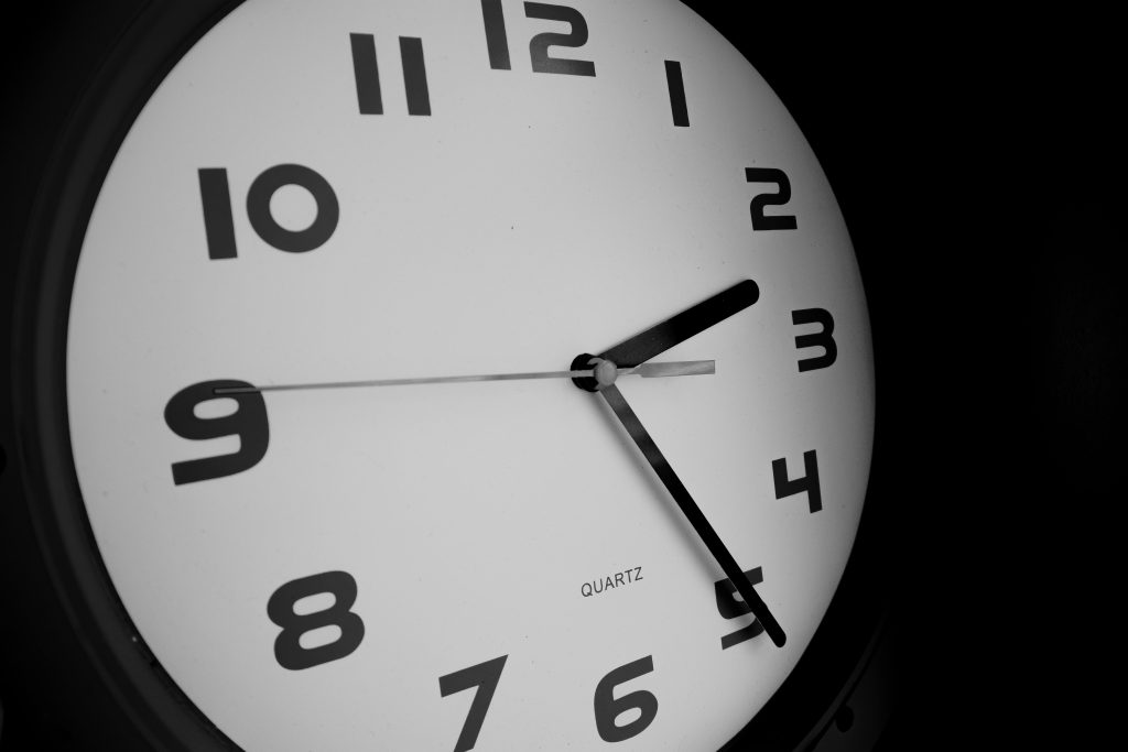 Black and white close-up of a wall clock showing nine o'clock. Gros plan en noir et blanc d'une horloge murale affichant neuf heures.