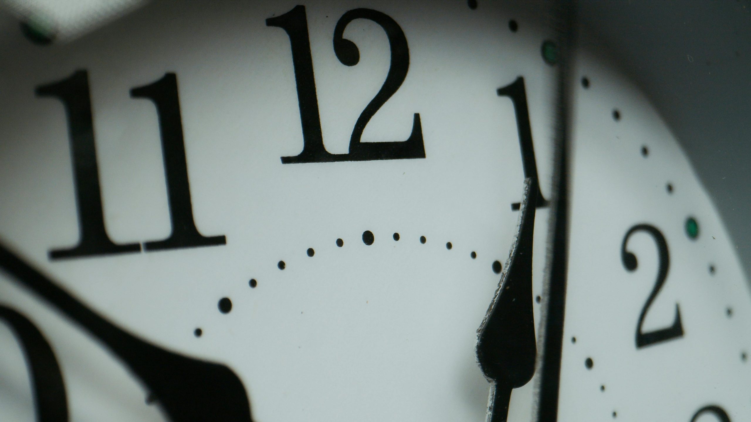 Macro photograph of a clock face showing numbers and minute markers. Photographie macro d'un cadran d'horloge montrant des chiffres et des marqueurs de minutes.