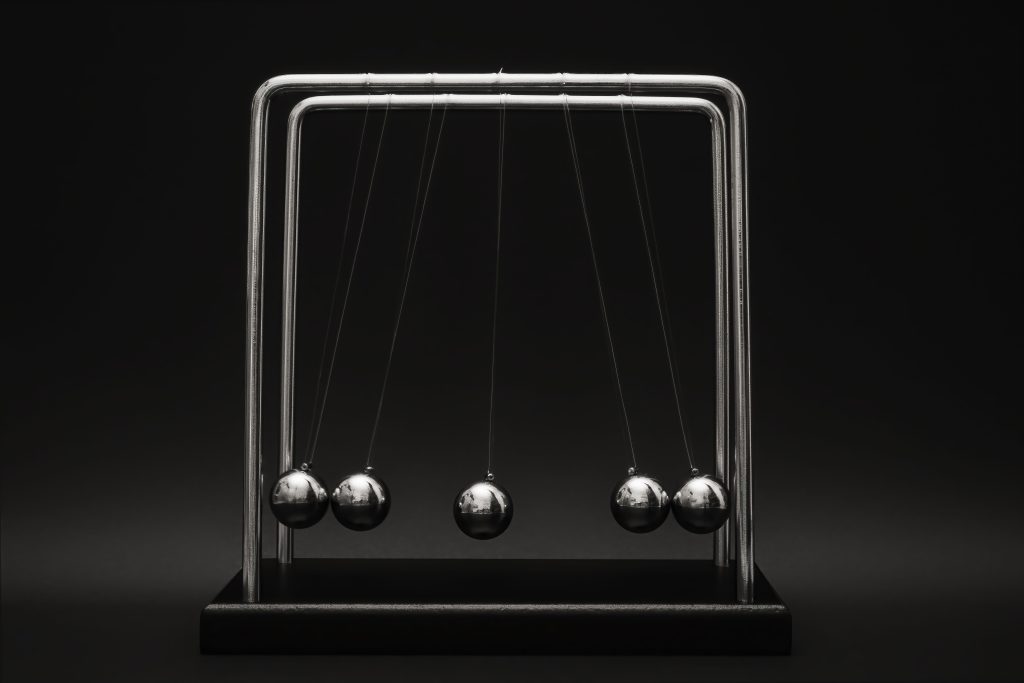 Newton's cradle for physics principles and motion study on a dark background. Le berceau de Newton pour l'étude des principes de physique et du mouvement sur fond sombre.