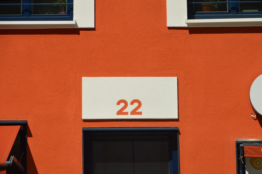 Vibrant orange building exterior with large number 22, modern design. Extérieur de bâtiment orange vibrant avec le grand numéro 22, design moderne.