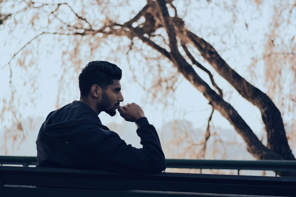 Man in deep thought sitting on a bench in a serene autumn park setting. Homme plongé dans ses pensées assis sur un banc dans un cadre de parc automnal serein.