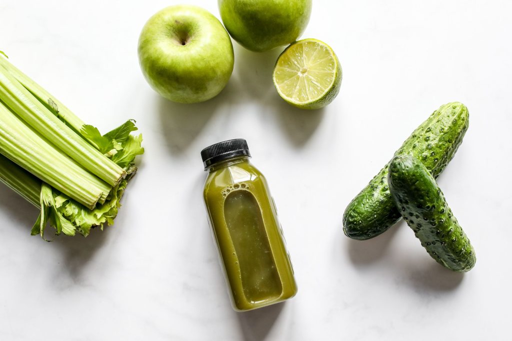 A top view of freshly extracted vegetable juice with celery, apples, lime, and cucumber. Une vue de dessus d'un jus de légumes fraîchement extrait avec du céleri, des pommes, du citron vert et du concombre.