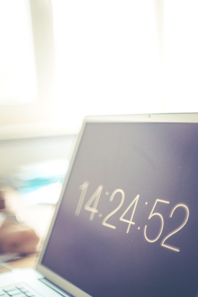 Écran d'ordinateur portable affichant une horloge numérique avec arrière-plan de bureau lumineux flou.