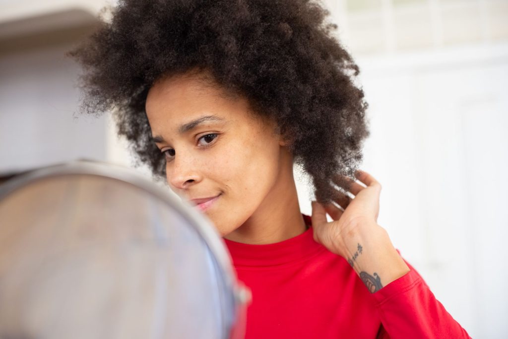 Femme qui coiffe ses cheveux fins devant un miroir