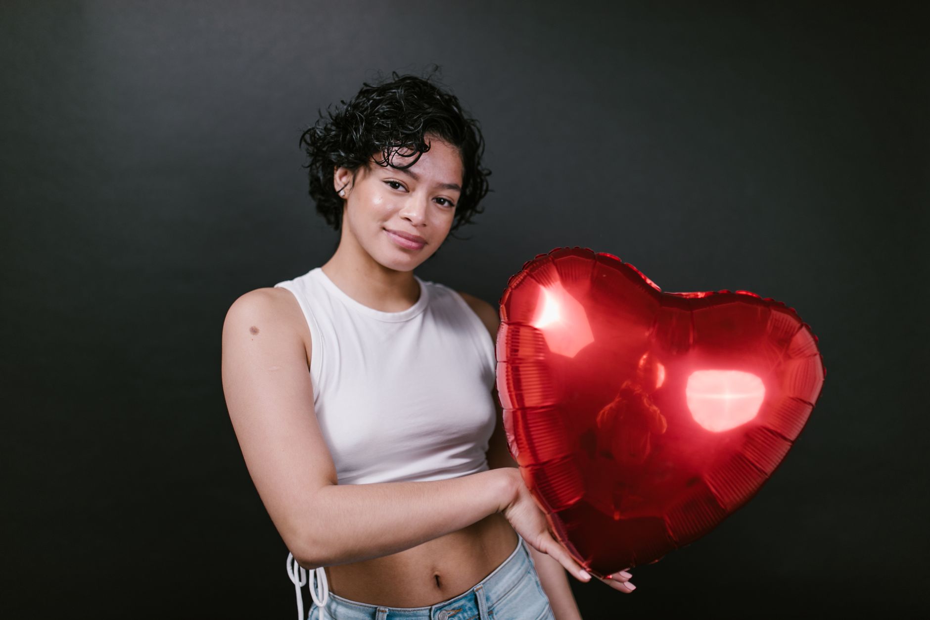 Jeune femme souriante avec un ballon en forme de coeur