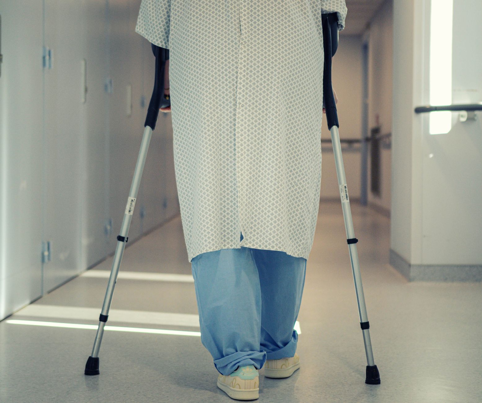 Patient qui marche avec des béquilles dans un couloir